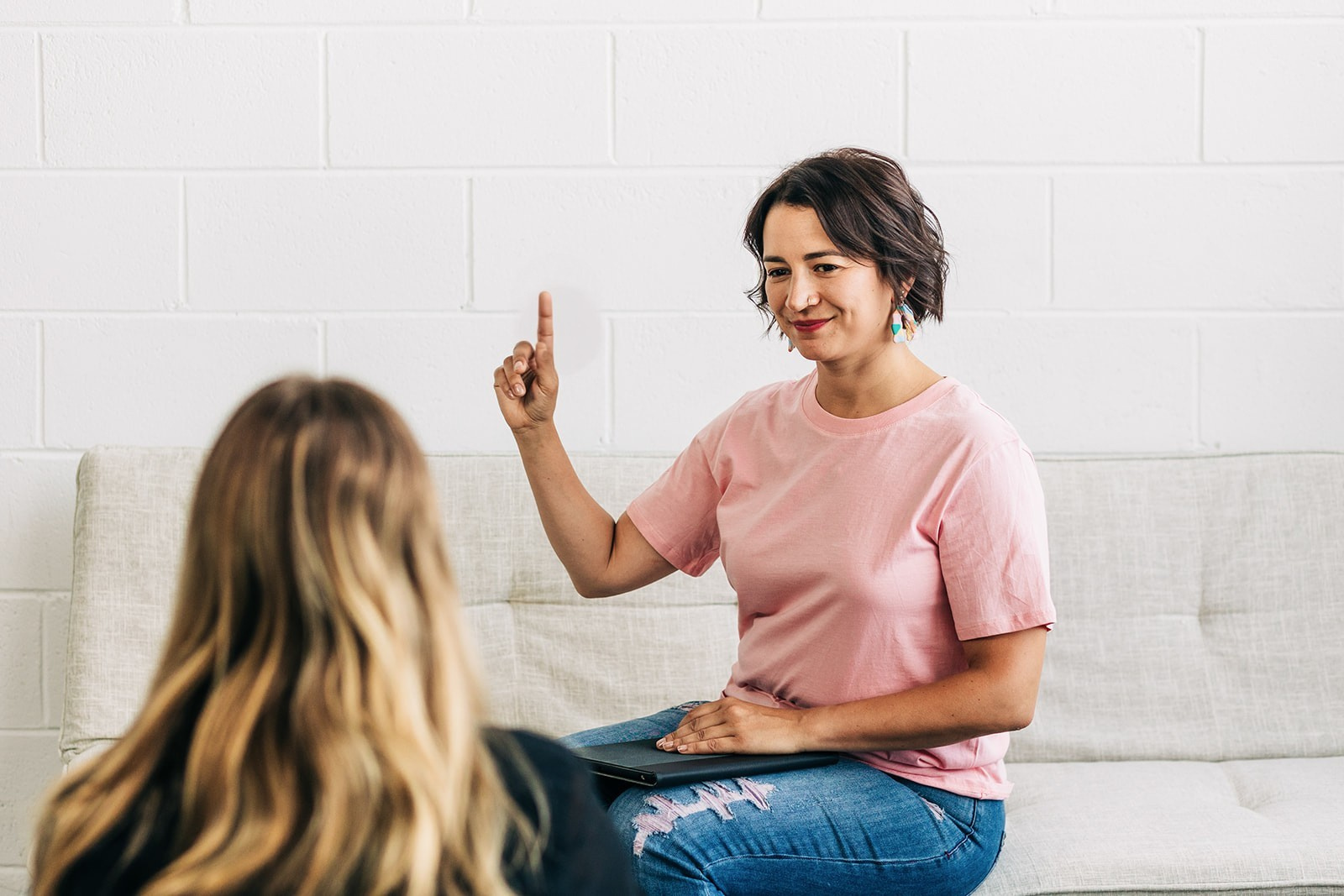  Marie Vakakis wearing a pink T-shirt, holding up one finger while demonstrating bilateral stimulation during an EMDR intensive therapy session.